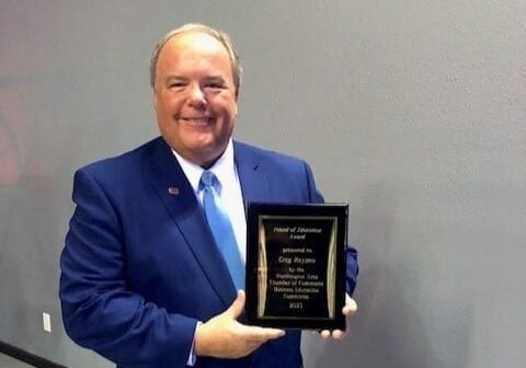 greg raymo holding a reward in a blue suite