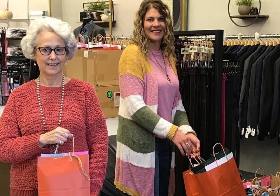 two women in a clothing shop holding red shopping bags
